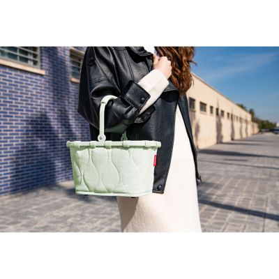 Kleiner Einkaufskorb von Reisenthel, Modell Carrybag XS, in Hellgrün mit Steppstruktur, von einer Person am Tragegriff getragen