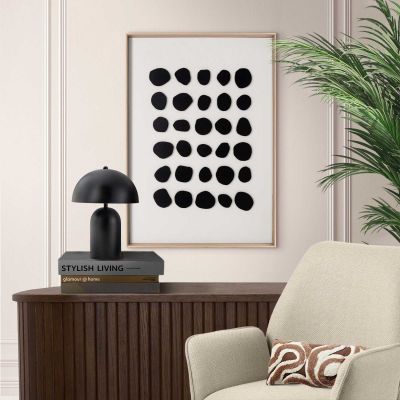 Das Wandbild „Black Dots“ in Schwarz-Weiß, 50 × 70 cm, hängt in einem eingerichteten Wohnraum und zeigt die Größenwirkung an der Wand.
