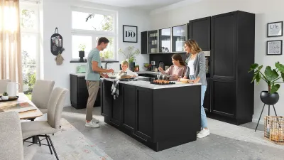 Junge Familie in edler schwarzer Landhausküche mit Interliving-Nolte Küchenmöbeln