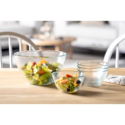 Transparente Glasschüsseln mit Salat und Zutaten auf Holztisch angerichtet