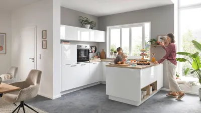 Gesamtansicht einer weißen Hochglanzküche – Mutter und Kind beim Backen