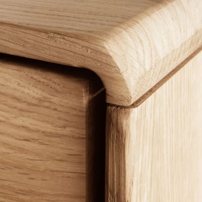 Nahaufnahme einer abgerundeten Ecke an einem Sideboard aus Holz mit sichtbarer Holzmaserung