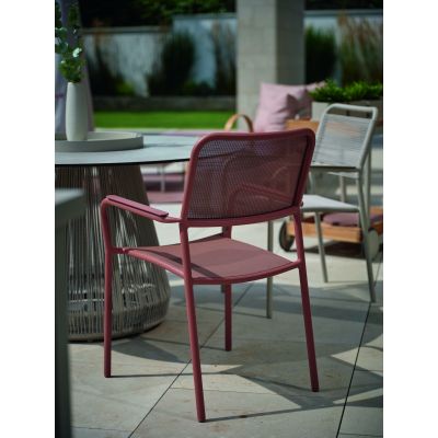 Gartenstuhl mit Armlehnen an einem runden Tisch auf einer Terrasse im Außenbereich