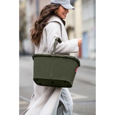 Einkaufskorb von Reisenthel, Modell Carrybag, in Dunkelgrün aus geripptem Cord, von einer Person am Griff getragen.