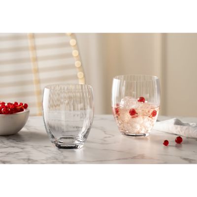 Zwei Trinkgläser eines gefüllt mit Eis und roten Beeren auf hellem Tisch