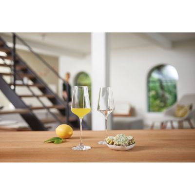 Zwei Weißweingläser auf Tisch mit Zitrone und modernem Wohnraum im Hintergrund