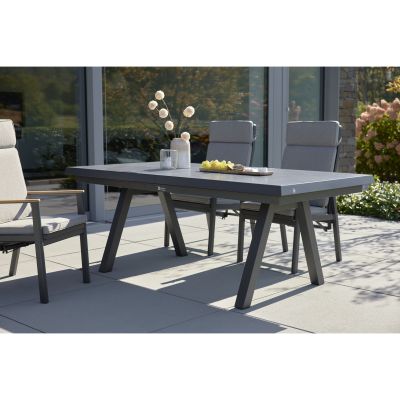 Gartentisch mit gepolsterten Gartenstühlen auf einer Terrasse vor einem Wohnhaus