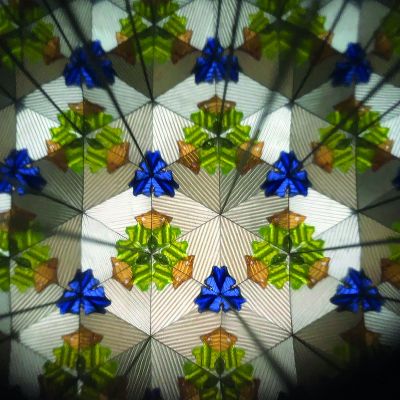 Blaues Kaleidoskop mit Weltraummotiv, mit einem zweiten symmetrischen Muster aus farbigen Figuren gezeigt.