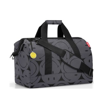 Reisetasche von Reisenthel, Modell Allrounder L, in Grau mit großflächigem Smiley-Muster, schräg von vorn mit Tragegriffen und Schultergurt.