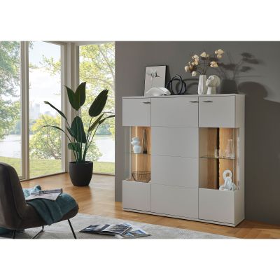 Weißes Highboard mit beleuchteten Glasfächern und Dekoration in einem hell eingerichteten Wohnraum