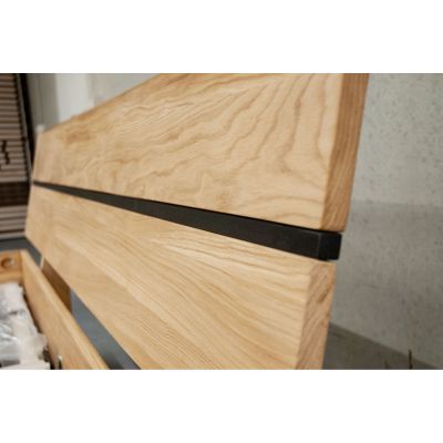 Nahaufnahme des Kopfteils aus Holz mit horizontalem schwarzen Metallstreifen und sichtbarer Holzmaserung