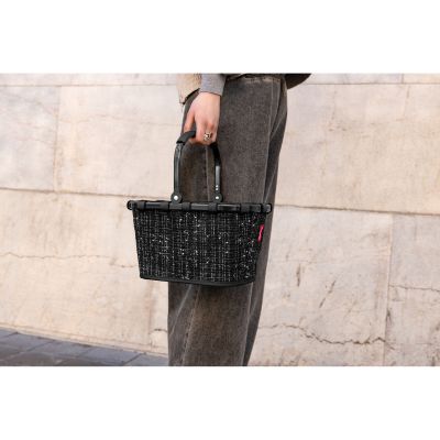 Kleiner Einkaufskorb von Reisenthel, Modell Carrybag XS, in Schwarz mit Bouclé-Struktur, von einer Person am Tragegriff getragen