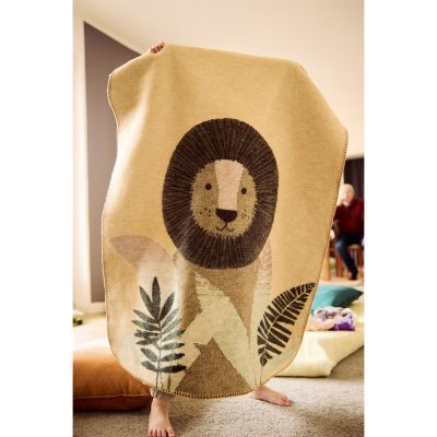 Babydecke Little King wird im Kinderzimmer hochgehalten und zeigt den großen Löwen auf ockergelbem Grund.
