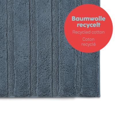 Vergrößerte Ansicht der rauchblauen Bademattenoberfläche mit länglichen Rippen und rotem Hinweisfeld zum Baumwollmaterial