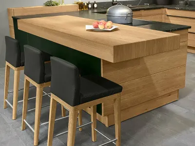 Nahaufnahme der Kücheninsel der Decker Bergamo Küche mit Barhockern mit schwarzem Lederbezug.