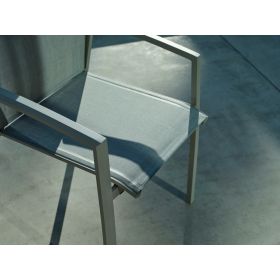 Nahaufnahme der textilen Sitzfläche und Armlehne eines Gartenstuhls, im Schatten und Sonnenlicht auf einer Terrasse.