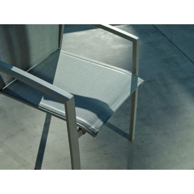 Nahaufnahme der textilen Sitzfläche und Armlehne eines Gartenstuhls, im Schatten und Sonnenlicht auf einer Terrasse.