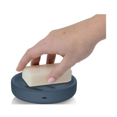 Eine Hand drückt ein helles Seifenstück auf die gerillte Ablagefläche einer tiefseeblauen Seifenschale