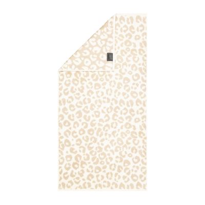 Handtuch in der Farbe Natur mit beigefarbenem Leopardenmuster auf hellem Grund und umgeschlagener Ecke; Vorderseite, Rückseite und kleines Textiletikett sind sichtbar.