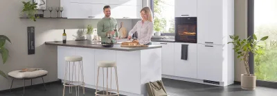 Junges, fröhliches Paar kocht gemeinsam in einer klassischen Küche bei Möbel Gruber in Ingolstadt