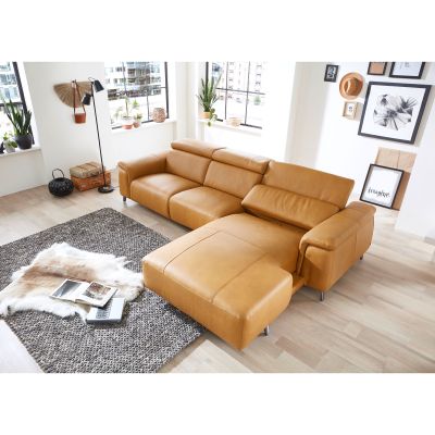 Cognacfarbenes Ecksofa mit Recamiere in einem hellen Wohnraum mit Teppich und Couchtisch