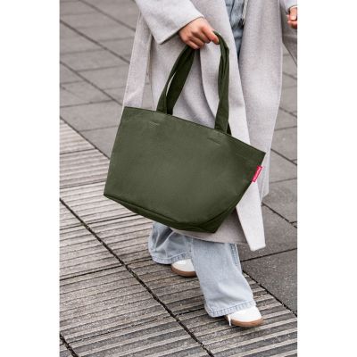 Shopper von Reisenthel, Modell Shopper M, in Dunkelgrün aus geripptem Cord, von einer Person an den Tragegriffen getragen.