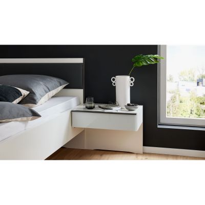 Weißer Nachttisch mit Schublade neben einem Bett in einem Schlafzimmer mit Fenster