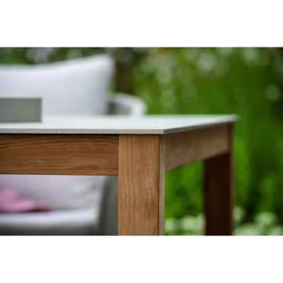 Nahaufnahme eines Tisches mit rechteckigem Holzgestell und heller Steinplatte, Ansicht von der Seite mit sichtbarer Tischkante