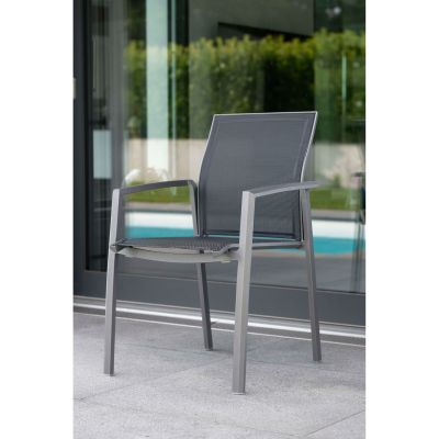 Ein grauer Stuhl mit Netzbespannung steht auf einer Terrasse vor einer Glasfront mit Blick auf einen Garten und einen Pool.