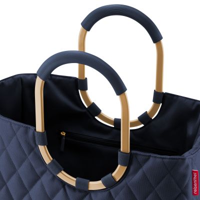 Detailaufnahme der ovalen Tragegriffe und des Innenfachs einer dunkelblauen Reisenthel Tasche mit Steppmuster