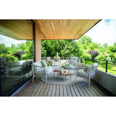 Terrassenszene mit mehreren Sesseln und zwei runden Beistelltischen aus Holz vor einer Glasfassade und Blick ins Grüne