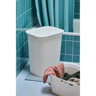 Weißer Wäschekorb mit Deckel in einem Badezimmer neben einer Badewanne