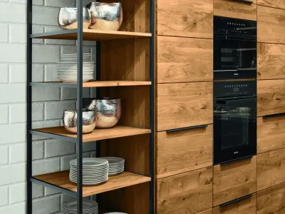 Massivholz-Wandschrank der Decker Küche Calezzo mit integriertem Backofen sowie Regalen aus schwarzem Stahl und Holz.