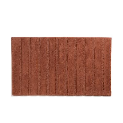 Terrakottafarbene Badematte Megan mit 60 × 100 cm und regelmäßig angeordneten Längsrippen.