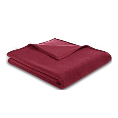 Gefaltete Wohndecke CottonSense brombeer in dunklem Beerenrot mit schmal eingefasster Kante auf weißem Hintergrund.