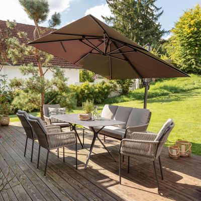 Gartentisch mit Stühlen auf einer Terrasse im Garten mit Sonnenschirm und Rasenfläche im Hintergrund