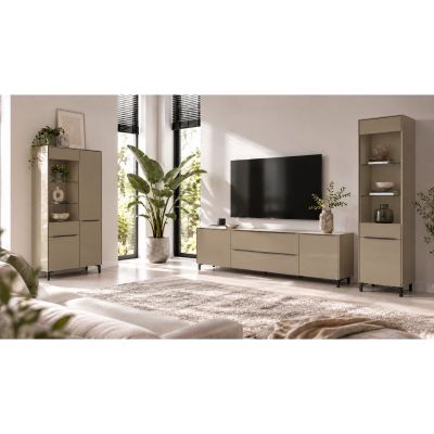 Helles Wohnzimmer mit einer schmalen taupefarbenen Vitrine rechts neben einem Lowboard mit Fernseher. Die Vitrine besitzt offene Glasablagen mit dekorativen Vasen und Schalen sowie ein geschlossenes Fach im unteren Bereich. Links im Raum steht eine breite