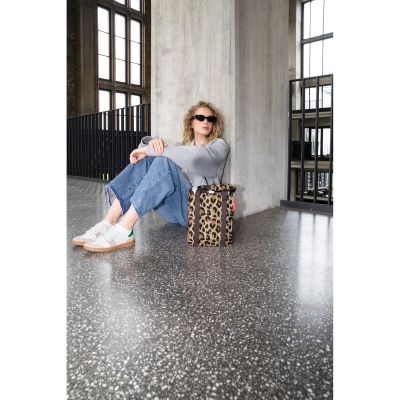 Flaschentasche von Reisenthel, Modell Bottlebag, in Beige und Braun mit Leopardenmuster, neben einer sitzenden Person mit eingesetzten Flaschen.