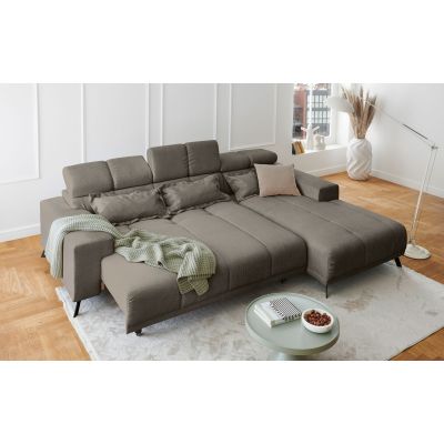 Hellgraues Ecksofa mit Ottomane rechts und ausgezogener Liegefläche in einem hellen Wohnzimmer mit Teppich und Couchtisch