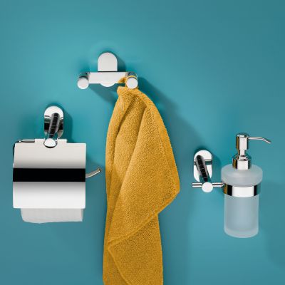 Silberfarbener Doppelhaken mit aufgehängtem gelbem Handtuch zwischen Toilettenpapierhalter und Seifenspender