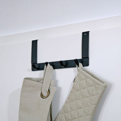 Schwarze Türgarderobe an einer weißen Tür mit zwei aufgehängten hellen Textilien