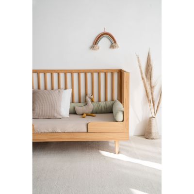 Holz-Kinderbett mit limegrüner Musselin-Bettschlange, Kissen und Stofftier in hellem, gemütlichem Kinderzimmer