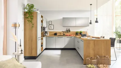 Gesamtansicht einer modernen Interliving Küche mit hellen Holzarbeitsflächen, hellgrauen Fronten und grifflosen Wandschränken