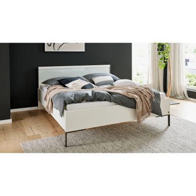 Weißes Bett mit Kopfteil in einem Schlafzimmer mit Bettwäsche und Tagesdecke