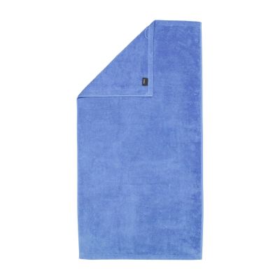 Duschtuch in der Farbe Capri mit umgeschlagener Ecke; Rückseite, Saum und kleines Textiletikett sind auf weißem Hintergrund sichtbar.