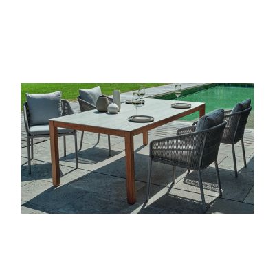 Rechteckiger Gartentisch mit mehreren Gartenstühlen auf Terrasse neben Pool und Grünfläche