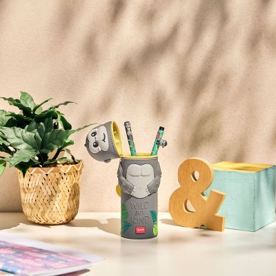 Graues 2-in-1-Silikon-Federmäppchen im Gorilla-Design, als Stiftebecher auf einem Schreibtisch neben Pflanze und weiteren Gegenständen dargestellt.