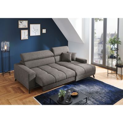 Dunkelgraue Wohnlandschaft mit Longchair rechts im Bild, vorgezogenen Sitzflächen und verstellbaren Kopfstützen in einem hellen Wohnraum