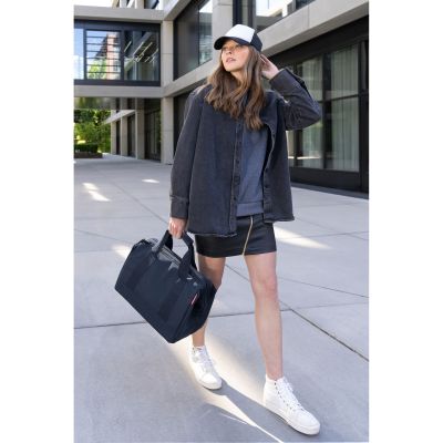 Frau trägt dunkelblaue Reisenthel Reisetasche in modernem Streetstyle-Outfit