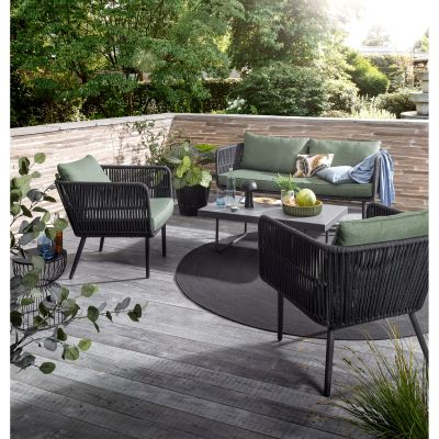 Gartenlounge mit Sofa Sesseln und Tisch auf einer Holzterrasse im Garten